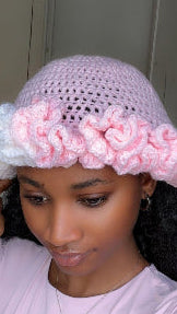 Person wearing a pink crochet hat with floral embellishments.